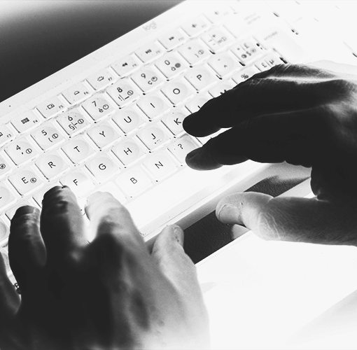 Hands typing on a computer keyboard where a negative filter has been applied to bring out the bright white of the keyboard like a treasure
